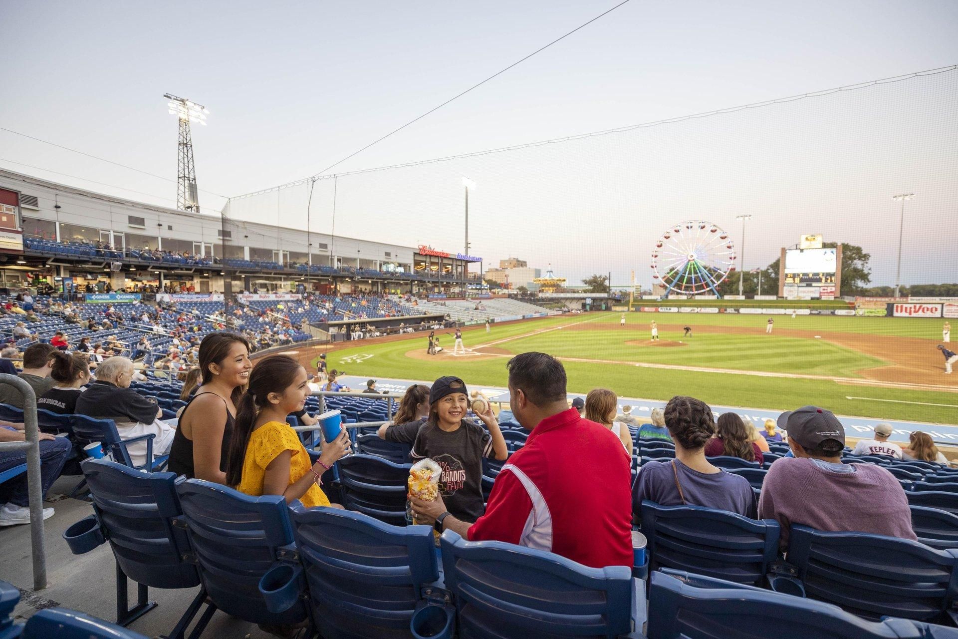A family sitting together in the stands at a baseball game.